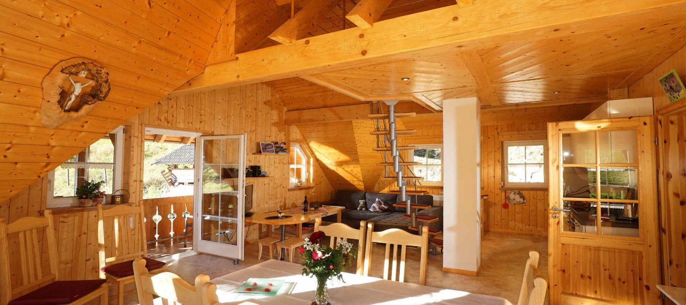 Ferienwohnung Blumenwiese Helles, einladendes Holzinterieur mit Esstisch und gemütlicher Sitzecke.